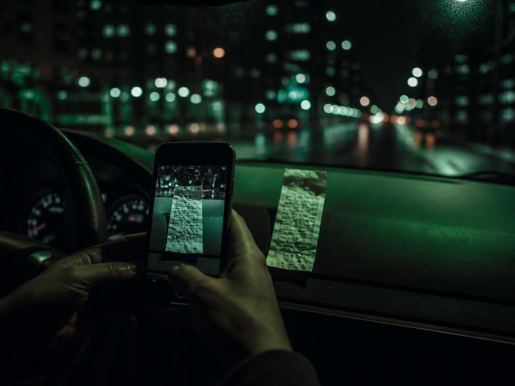 Gig driver photographing a gas receipt on the dashboard at night
